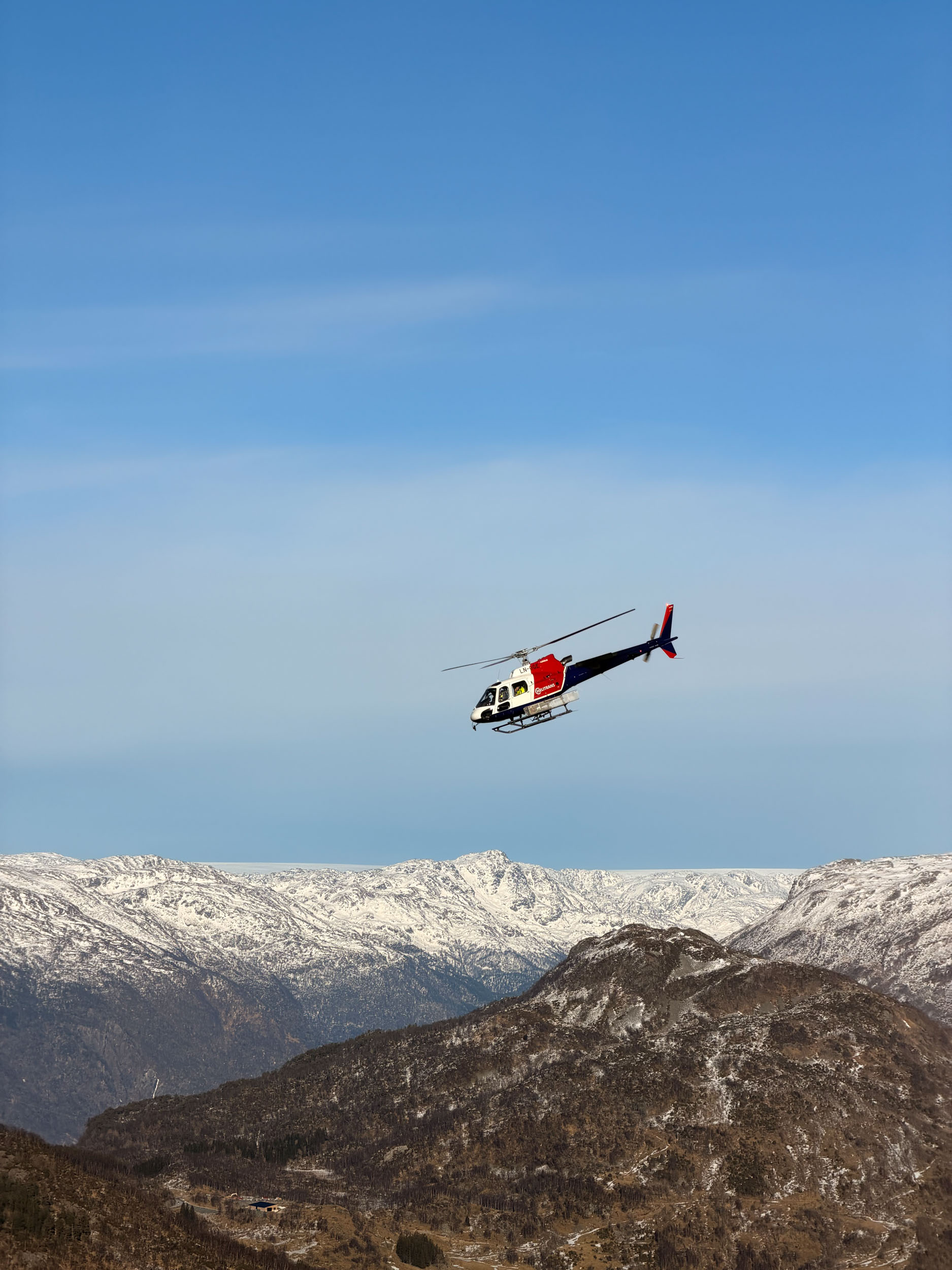 Bilde av et helikopter som flyr over norsk natur