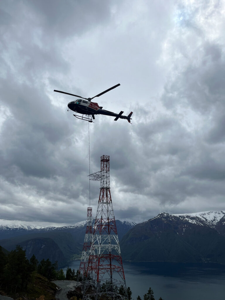 Bilde av et helikopter i luften som frakter master