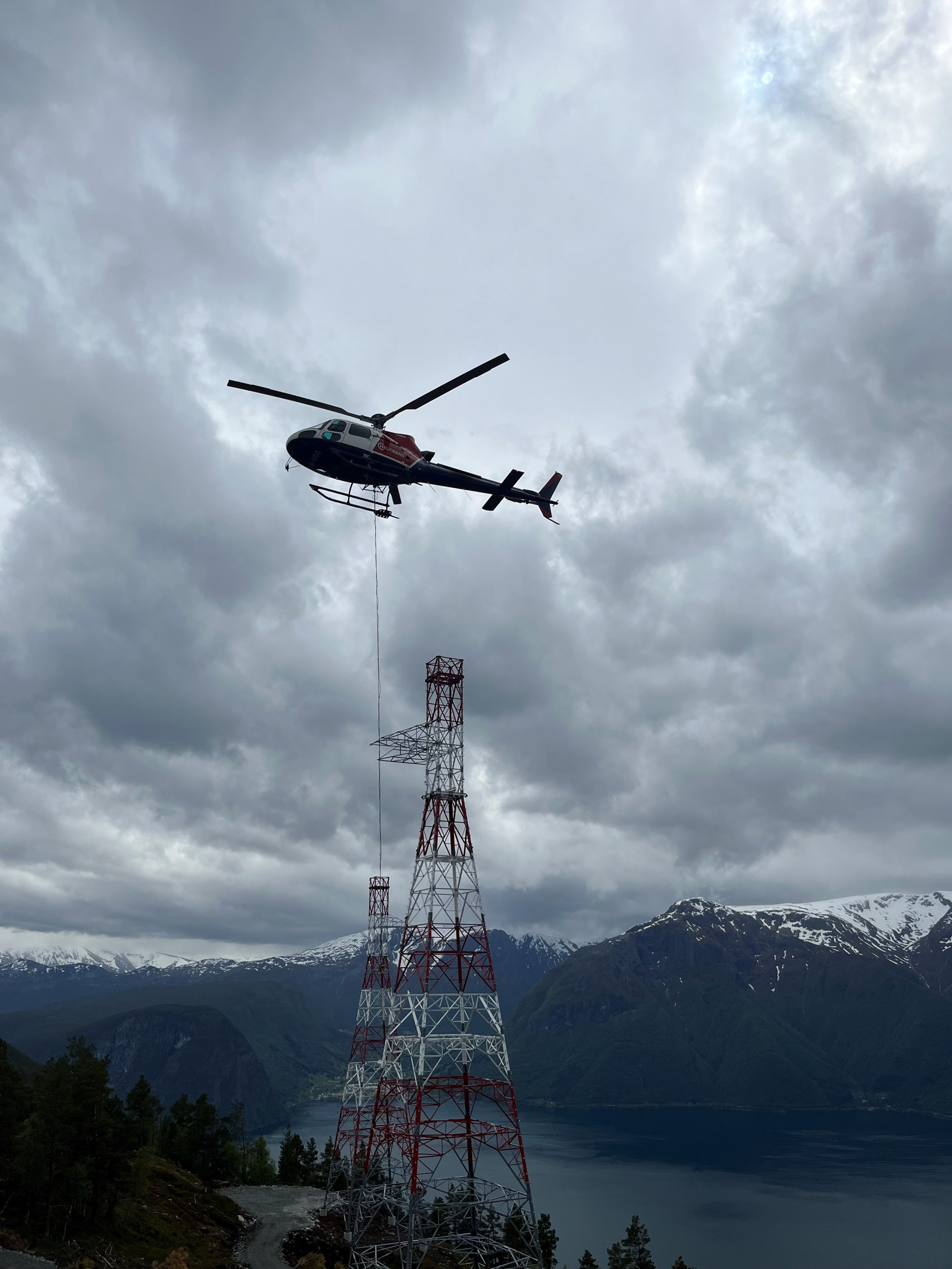Bilde av et helikopter i luften som frakter master