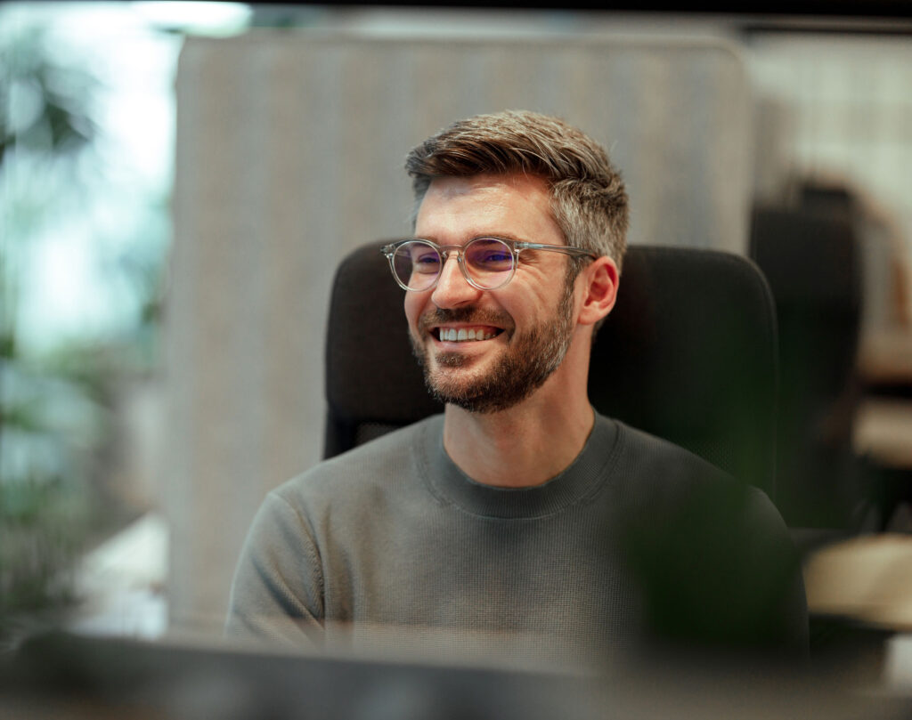 Bilde av en mann som sitter og ser mot en pskjerm